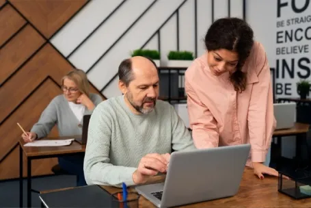 une formatrice en cours de formation devant un pc avec un senior