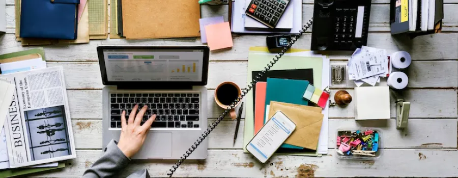 femme assise devant son ordinateur portable avec plein de document administratif à gérer