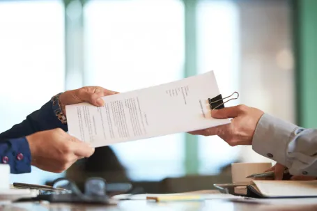 mains délégant un document administratif à une autre main